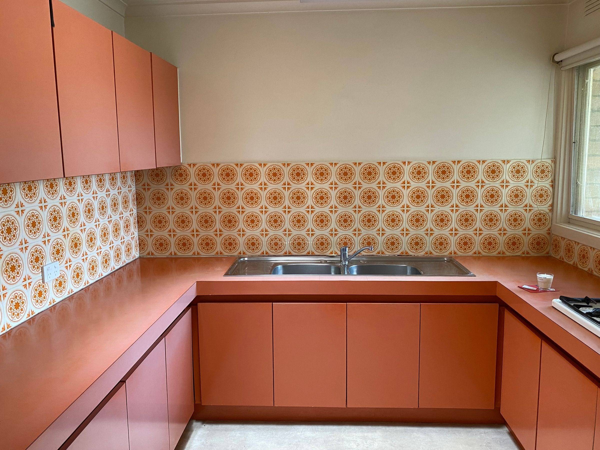 Ancienne cuisine en U aux façades et plans de travail orange, carrelage à motifs