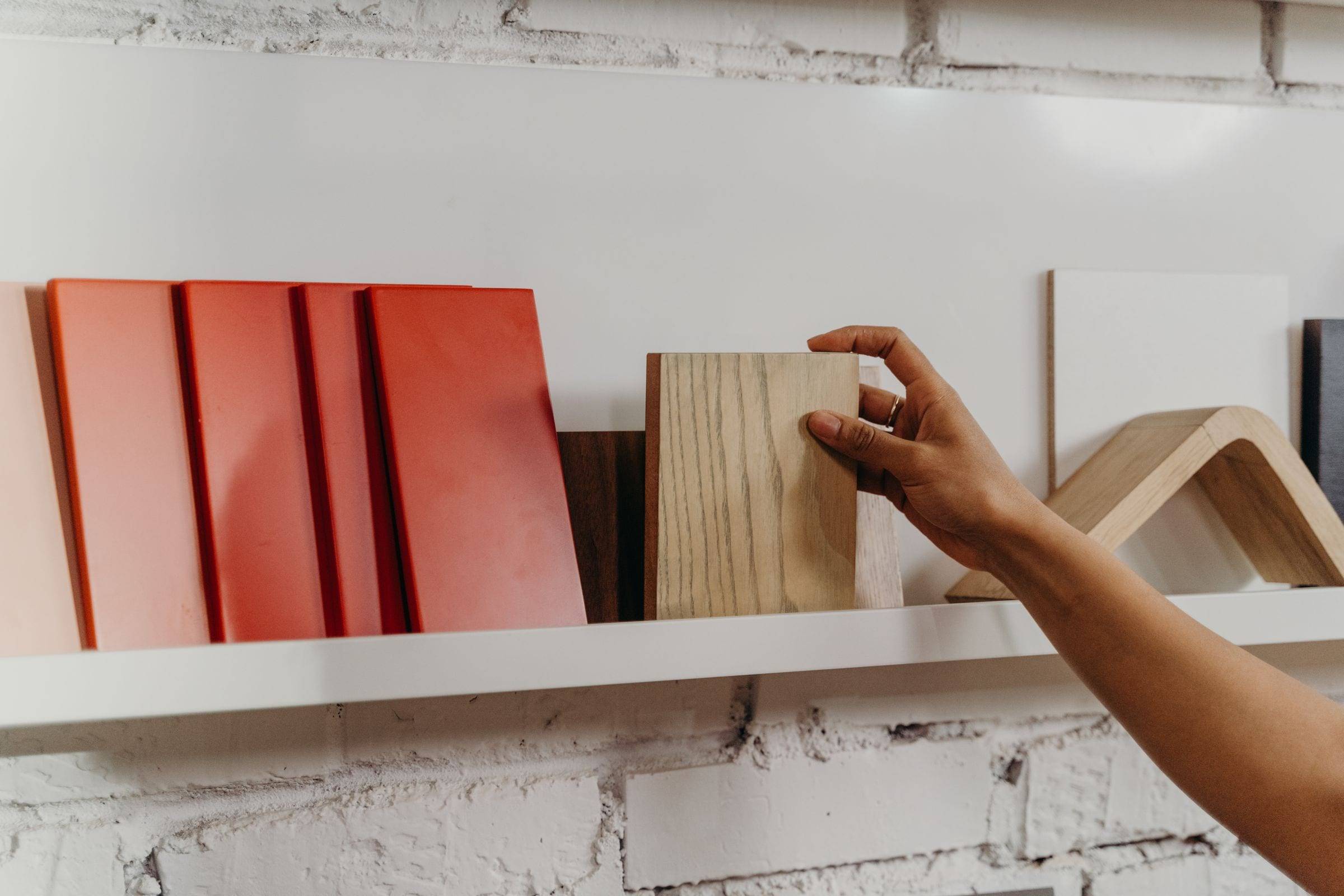 Une main choisit un échantillon de façade en bois parmi des échantillons colorés